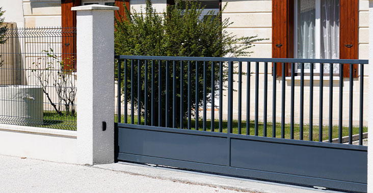 Fachada de casa moderna de un piso con reja de perfiles de acero colocados de mabnera vertical en la entrada