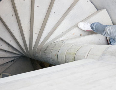 Persona descendiendo por escalera de caracol de concreto