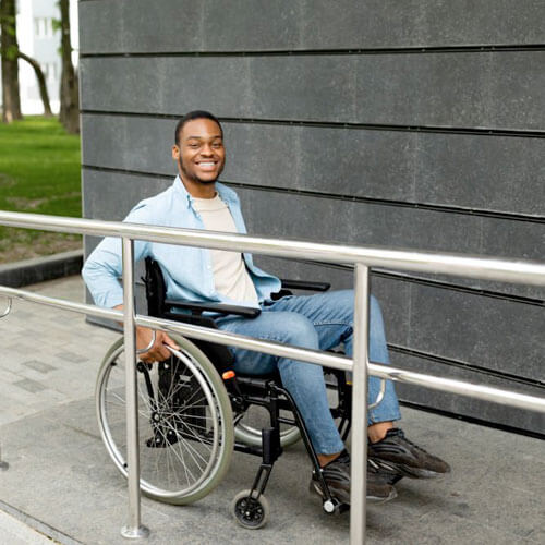 Hombre en silla de ruedas subiendo por rampa de cemento
