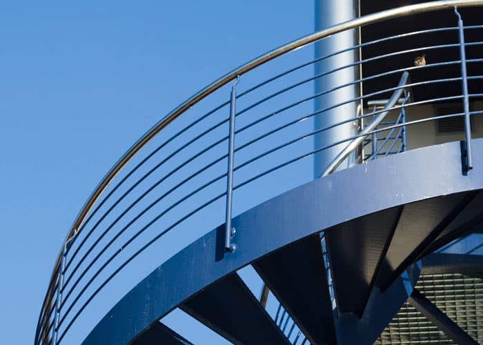 Escalera exterior de caracol equipada con barandales modernos de acero inoxidable