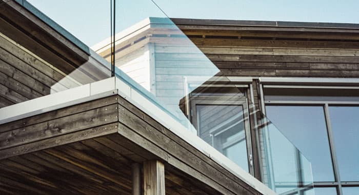 Terraza de una casa de madera con barandal moderno de vidrio templado sin pasamanos