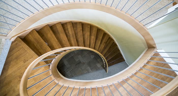 Vista cenital de escalera con diseño helicoidal y barandales modernos de madera curvados