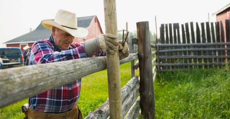 Vaqueros instalando una cerca perimetral para rancho al costado de una casa