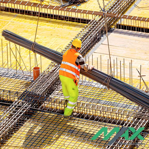 Trabajador de la construcción guiando un paquete de varillas sobre estructuras hechas con aceros de refuerzo