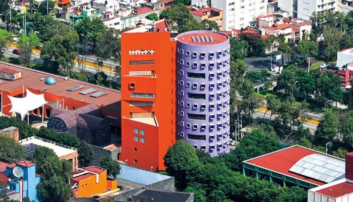 Vista aérea de las coloridas torres del CENART: un cilindro púrpura acompañado de un prisma triangular