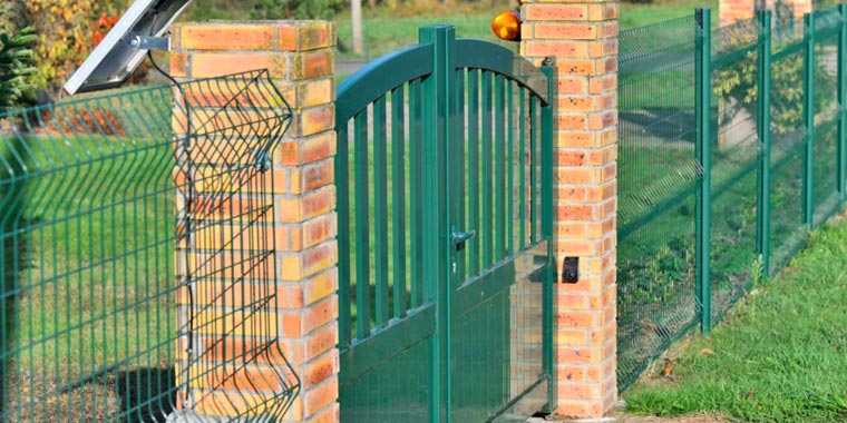 Barda con paneles de reja de acero color verde en un entorno rural