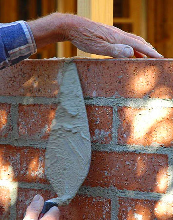 Manos de albañil construyendo una barda con tabiques