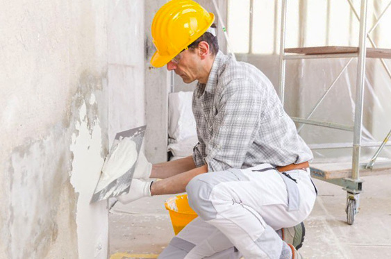 Trabajador de la construcción aplicando mezcla de cemento blanco sobre una superficie sin recubrimiento