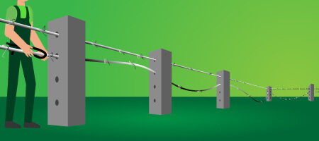 Persona realizando la instalación de las hileras de alambre de púas a través de los postes de concreto - Cercar con alambre de púas