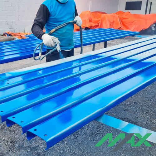 Trabajador aplicando capa de pintura sobre perfiles de acero