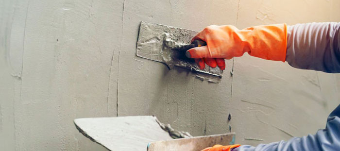 Trabajador aplicando una capa de cemento gris sobre muro