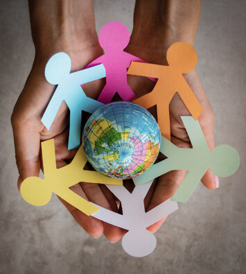 Manos sosteniendo un globo terraqueo y figuras de papel