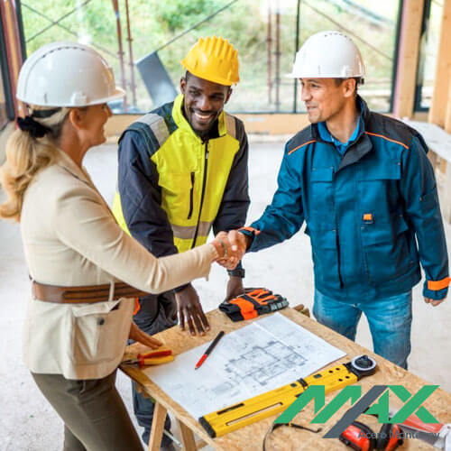 Arquitectos saludándose sobre mesa con planos e instrumentos de medición