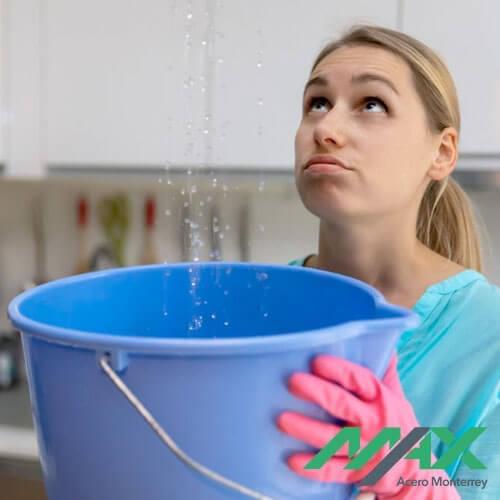 Mujer utilizando cubeta para evitar encharcamientos por filtraciones de agua