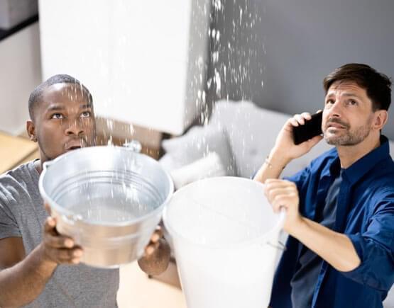 Pareja colocando cubetas para atrapar el agua de las filtraciones de agua