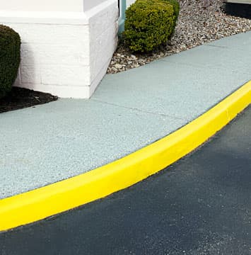 Guarnición de una banqueta recién pintada de color amarillo.