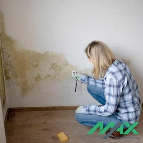 Adulto usando cubrebocas dentro de una habitación llena de moho por humedad en paredes