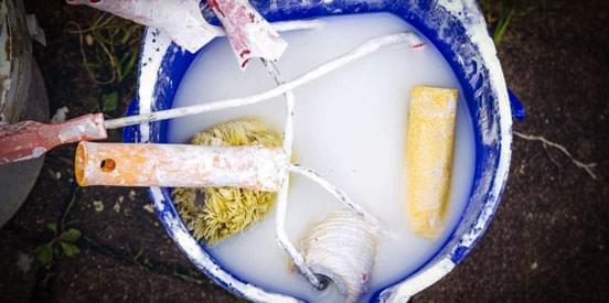 Cubeta con rodillos listos para limpieza después de aplicación de impermeabilizante