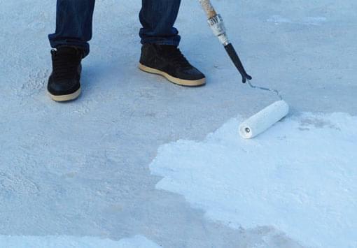 Persona aplicando impermeabilizante elastomérico sobre un techo