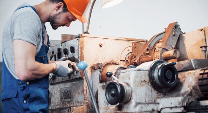 Trabajador de planta metalúrgica realizando reparación de máquina - Mantenimiento industrial
