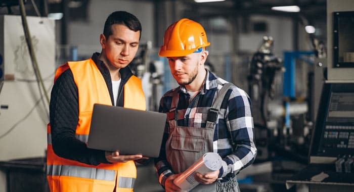 Trabajadores en instalaciones industriales observando laptop - Mantenimiento industrial