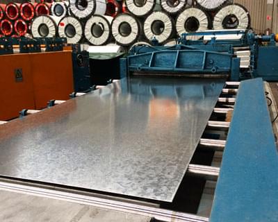 Lámina lisa galvanizada pasando por un tren de laminación en una fábrica