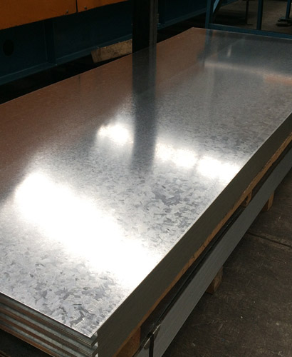 Piezas de lámina lisa de acero acomodadas unas sobre otras dentro de una bodega de acero