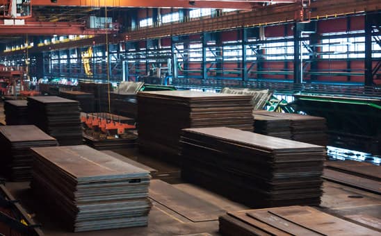 Hojas de lámina negra estibadas en diversos grupos dentro de un almacén