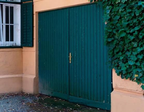 Puerta de casa compuesta de lámina tipo tablero de color azul.