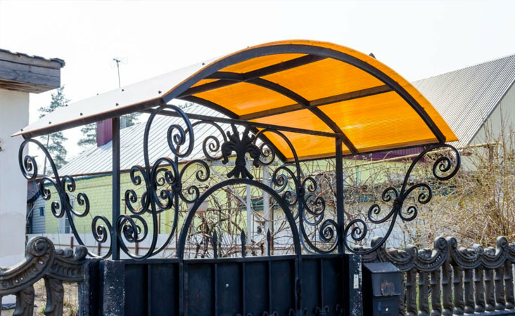 Marquesina de policarbonato celular de color naranja sobre la puerta de entrada de una casa