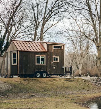 Tiny House rodante hecha de madera estacionada a la orilla de un lago