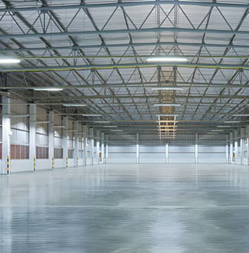 Vista panorámica del interior de una nave industrial vacía, construida con concreto y acero