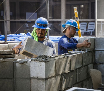 Trabajadores levantando un muro de ladrillo en una obra negra en desarrollo
