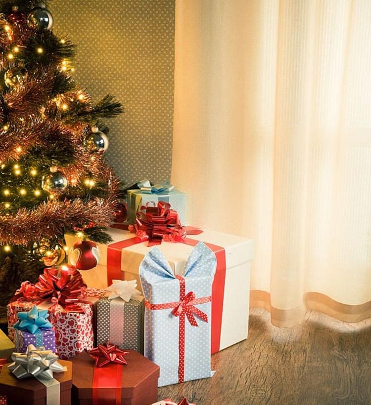 Árbol de Navidad adornado con regalos en la base del tronco