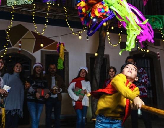 Familias mexicanas rompiendo la pinata en las calles de mexico durante una posada