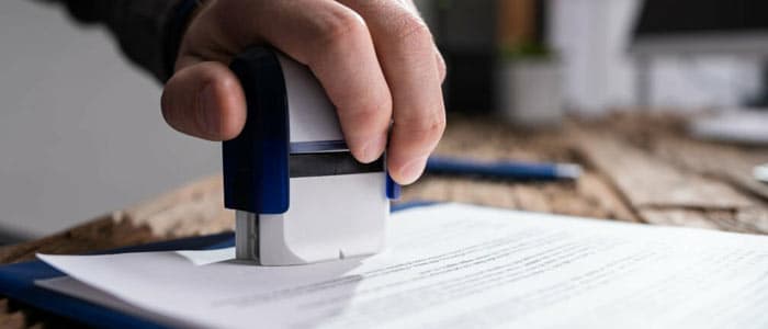 Mano de una persona sellando un documento en referencia a lo que es una licitación de carácter público