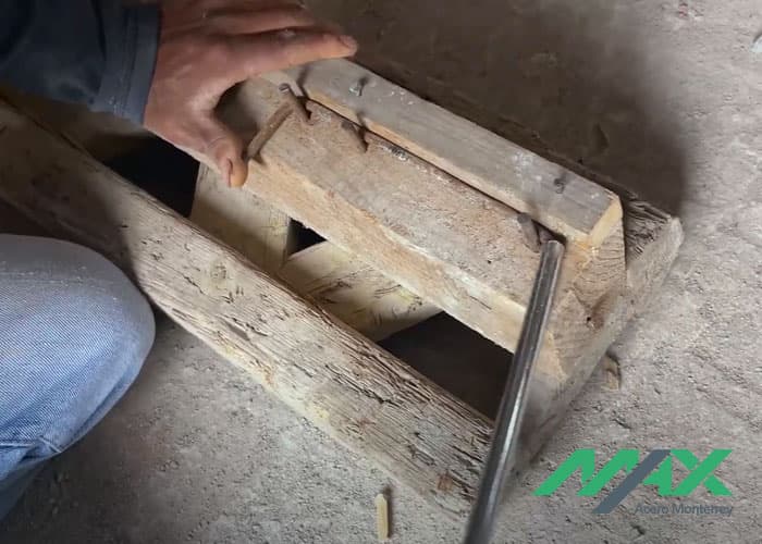 Trabajador doblando tramo de alambrón a 90 grados sobre estructura de madera para hacer estribos