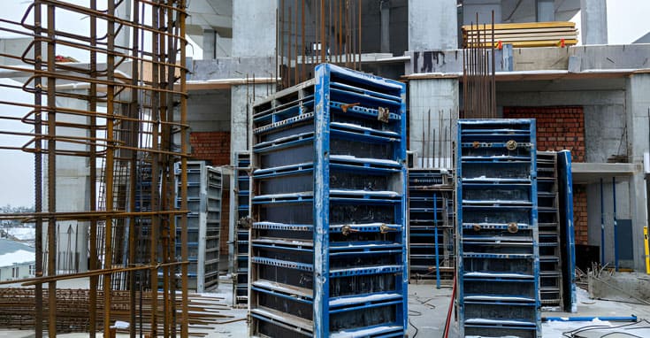 Construcción en curso con cimbras metálicas y varillas en un edificio en estructura. Materiales apilados