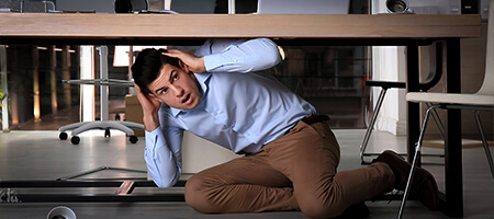 Hombre sentado abajo de su escritorio con las manos en la cabeza