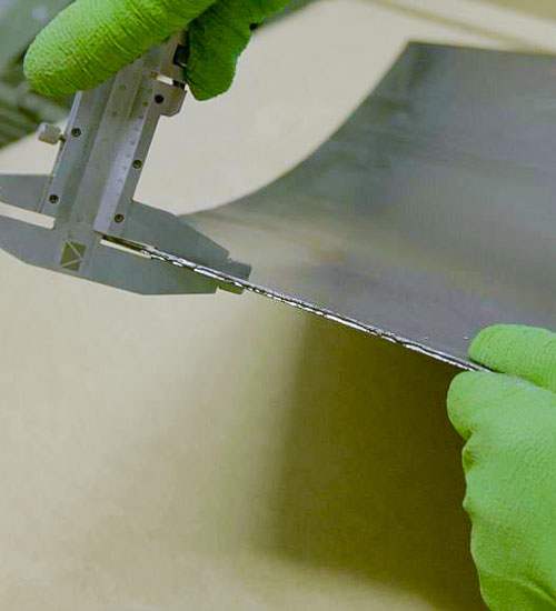 Trabajador utilizando un medidor de espesor sobre una lámina de acero