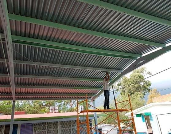 Hombre colocando polines monten como estructura para techo de lámina acanalada.