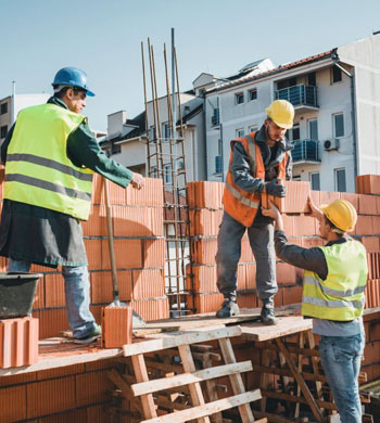 Trabajadores en construcción de muro con castillo al centro