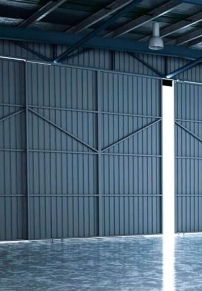 Puerta de una bodega edificada con lámina tipo tablero de color gris.